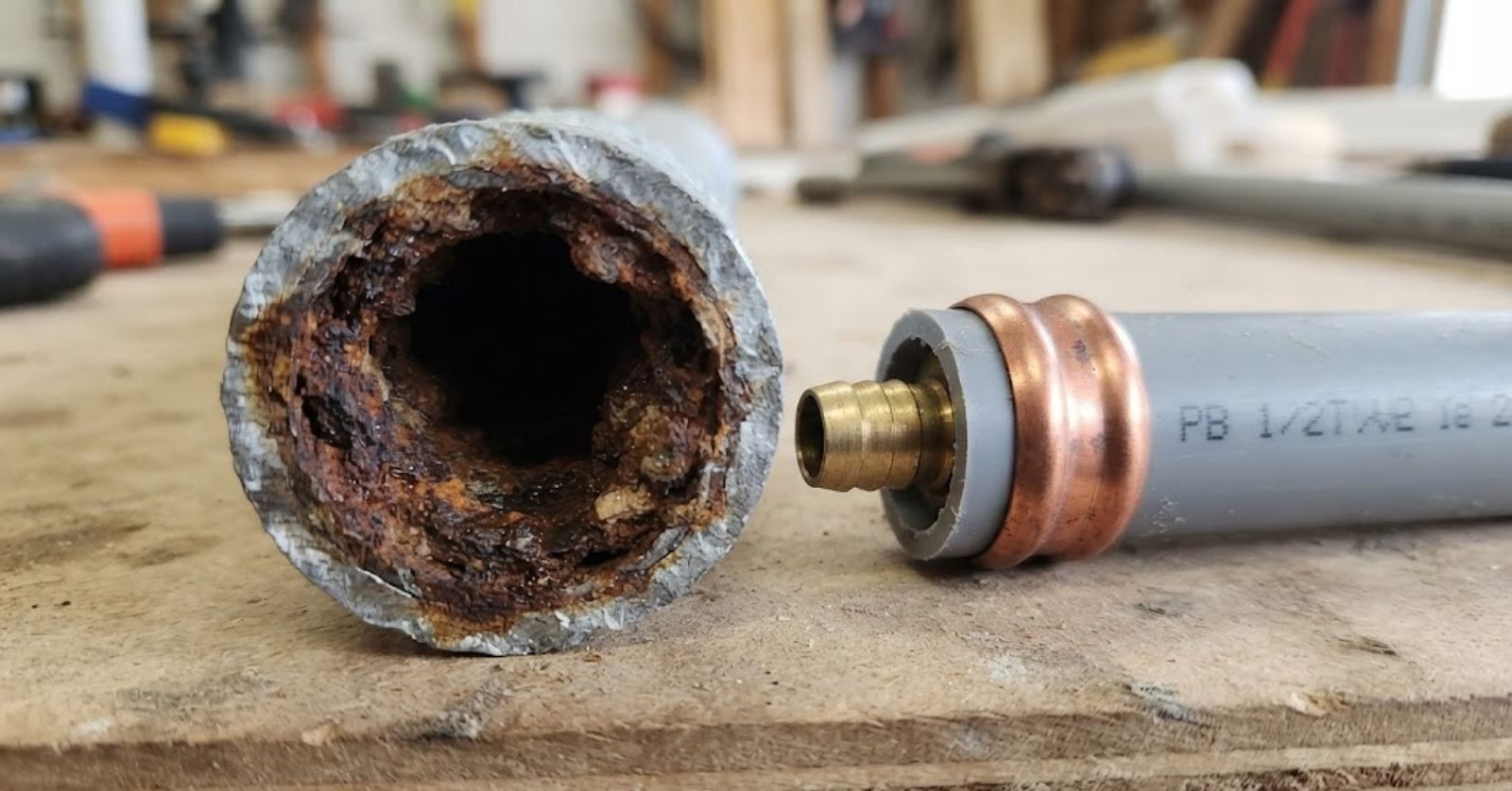 Corroded galvanized pipe beside gray polybutylene plumbing