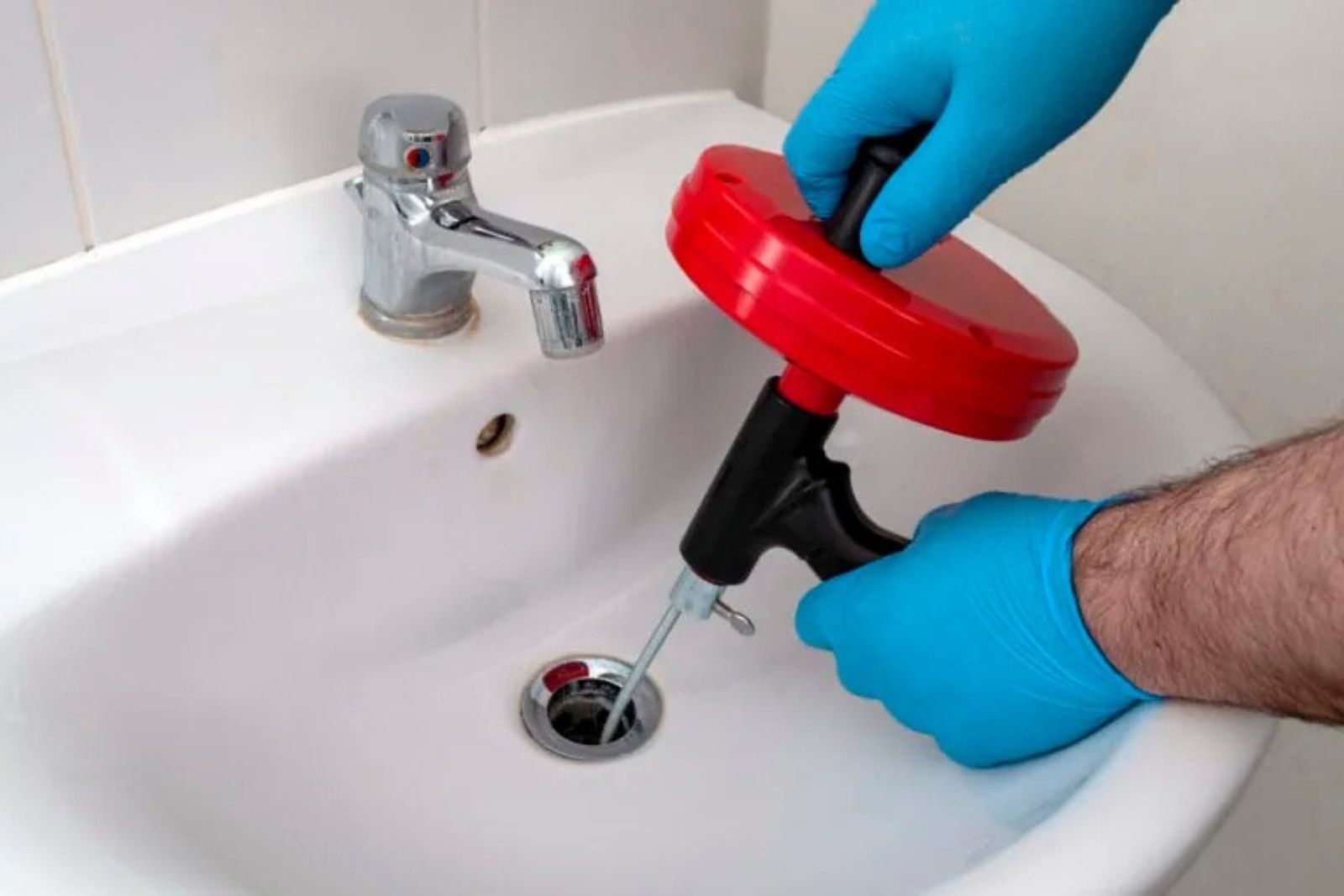 Plumber clearing a clogged kitchen drain with a drain snake